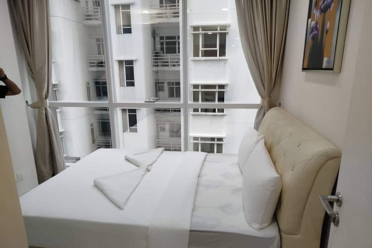 Una habitación de hotel con cama, cortinas, ventana y un cuadro en la pared.