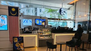 L’intérieur d’un café, avec un comptoir, des vitrines et un espace pour s’asseoir.