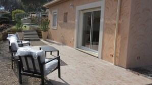 A patio with outdoor seating, a sliding glass door, and a stone-tiled floor. - VILLA CARA (Mougins)