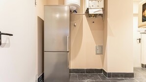 Una cocina con un refrigerador de doble puerta, un horno empotrado y un estante pequeño con una toalla.