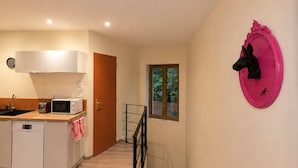 Una cucina moderna con lavastoviglie, microonde e tostapane. Una scala conduce a una piattaforma con una finestra.