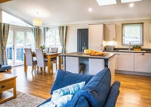A modern kitchen with a dining area, a sofa, and a view of the outdoors. - New for 2024, Yr Arenig is a home from home luxurious two bedroom lodge. (Bala,)