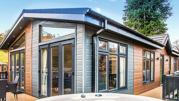 Ein modernes Haus mit großen Glasfenstern, einem Whirlpool und einer Terrasse.