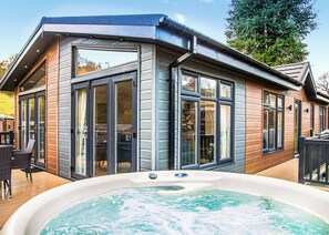 A modern house with large glass doors, a hot tub, and a deck. - New for 2024, Yr Arenig is a home from home luxurious two bedroom lodge. (Bala,)