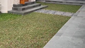 A modern house with a stone facade, a wooden door, and a well-maintained lawn. - Guru Darma Villa Newly Built September 2025 (Taro)