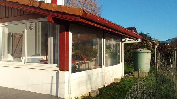 A house with a large window, a wooden door, and a red roof. - Rental Apartment Type T2 Curistes ou Vacanciers (Halsou)