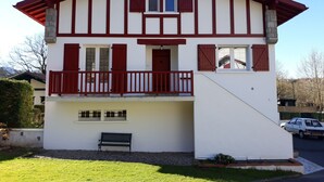 A two-story house with a balcony, a bench, and a car parked in the driveway. - Rental Apartment Type T2 Curistes ou Vacanciers (Halsou)