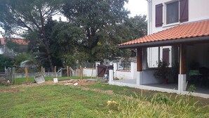 A residential property with a fenced yard, a garden area, and a house with a tiled roof. - Rental Apartment Type T2 Curistes ou Vacanciers (Halsou)