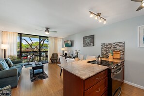 A modern kitchen with a granite countertop, stainless steel appliances, and a dining area with a table and chairs. - Charming 1-bedroom condo in South Maui, perfect for a relaxing getaway! - Maui Vista 2216 (Kihei)
