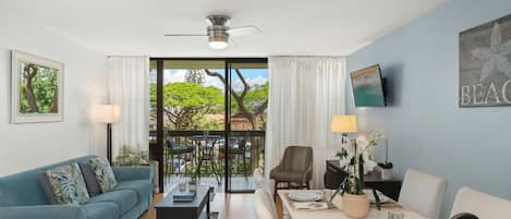 Una sala de estar moderna con un sofá, una mesa de comedor, una silla, un televisor y un ventilador de techo.