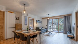 Ein moderner Wohnraum mit Essbereich, einer Couch und einem Balkon mit Blick.