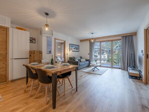 A modern living space with a dining area, a sofa, and a balcony with a view. - Central Chamonix apartment with parking, 2 bedrooms (Chamonix-Mont-Blanc)