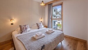 Ein Schlafzimmer mit einem großen Bett, zwei Wandleuchten, einem Fenster mit Ausblick und einer Pendelleuchte.