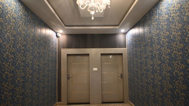 A hallway with two double doors, a chandelier, and patterned wallpaper. - sandhya paying guest house (Varanasi)