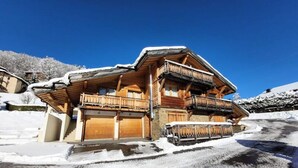 Un chalet en bois doté de plusieurs balcons, d’un garage et surplombant un paysage enneigé.