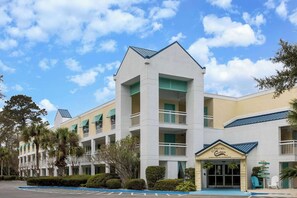 A hotel with a central tower, multiple balconies, and a front entrance with a sign. - Hotel Carolina a Days Inn by Wyndham (Hilton Head Island)