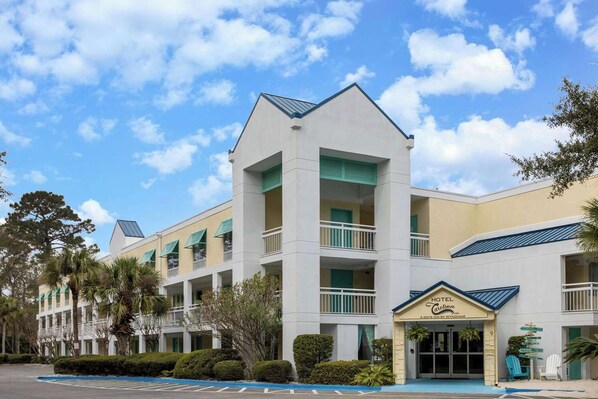 A hotel with a central tower, multiple balconies, and a front entrance with a sign. - Hotel Carolina a Days Inn by Wyndham (Hilton Head Island)