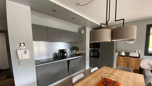 A modern kitchen with grey cabinets, a coffee maker, and a built-in oven. - 4-Room Apartment, 6 People, Sauna, Hammam, Parking, Wifi (Châtel)