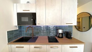 Una cucina compatta con lavello, fornello e forno a microonde.