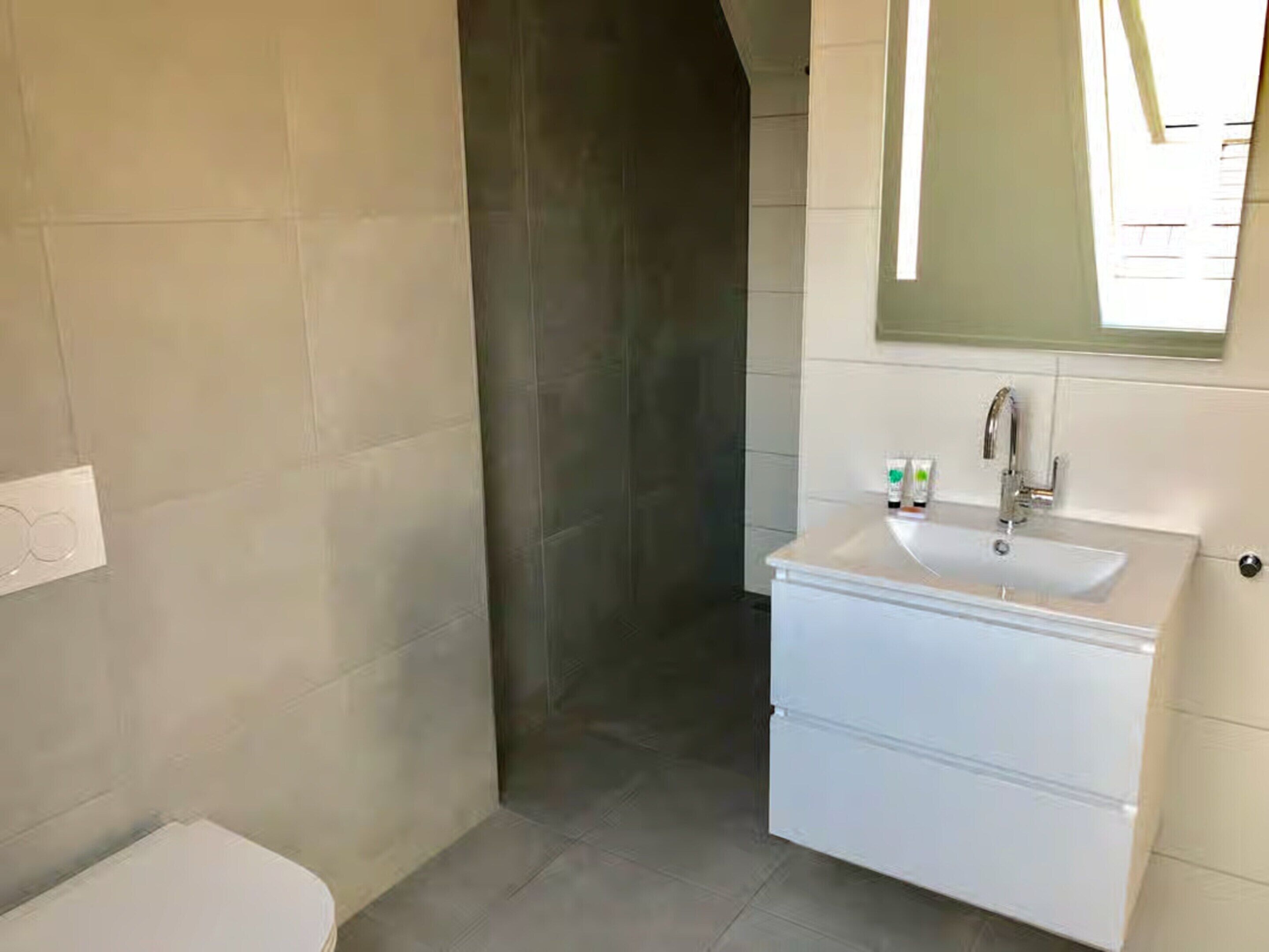 A bathroom with a white sink, mirror, and tiled walls.