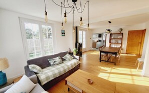 A spacious living area with a sofa, wooden dining table, and a kitchen in the background. - The *** ocean pearl (Gujan-Mestras)