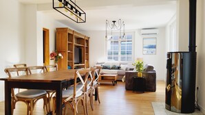 Een ruime woonkamer met een houten eettafel en stoelen, een bank en een televisie.