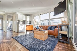 A modern living room with a sofa, a wicker coffee table, and a television. - Bright Base With Coastal Access (Ribnitz-Damgarten)