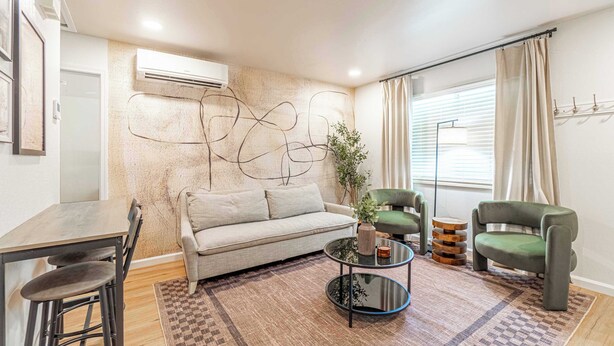 Una sala de estar moderna con un sofá, dos sillones, una mesa de centro y una zona de comedor con una mesa y sillas.