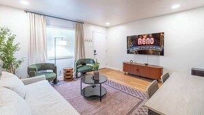 Una sala moderna con un sofá, dos sillones, una mesa de centro redonda, un televisor y un mueble de madera.