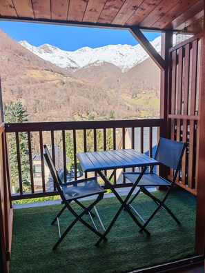 Ein Holzbalkon mit Tisch und Stühlen mit Blick auf eine gebirgige Landschaft.