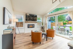 Un salon moderne doté d’une cheminée, d’une grande fenêtre et offrant une vue sur la terrasse extérieure.