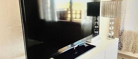 A flat-screen TV on a stand with a chessboard in front.