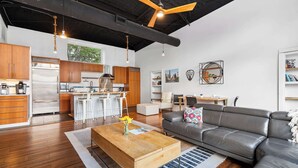 A modern kitchen with wooden cabinets, a stainless steel refrigerator, and a dining area with a white table and chairs. - Contemporary 3BR Country Gem Swim Spa Fire Pit (Dripping Springs)