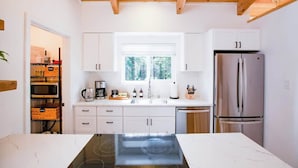 Eine moderne Küche mit weißen Schränken, einem Edelstahl-Kühlschrank und einem eingebauten Backofen.