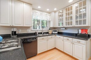 A modern kitchen with white cabinets, a black countertop, a dishwasher, a stove, and a microwave. - Truckee Mountain Retreat Family Friendly 3BR 2BA (Truckee)