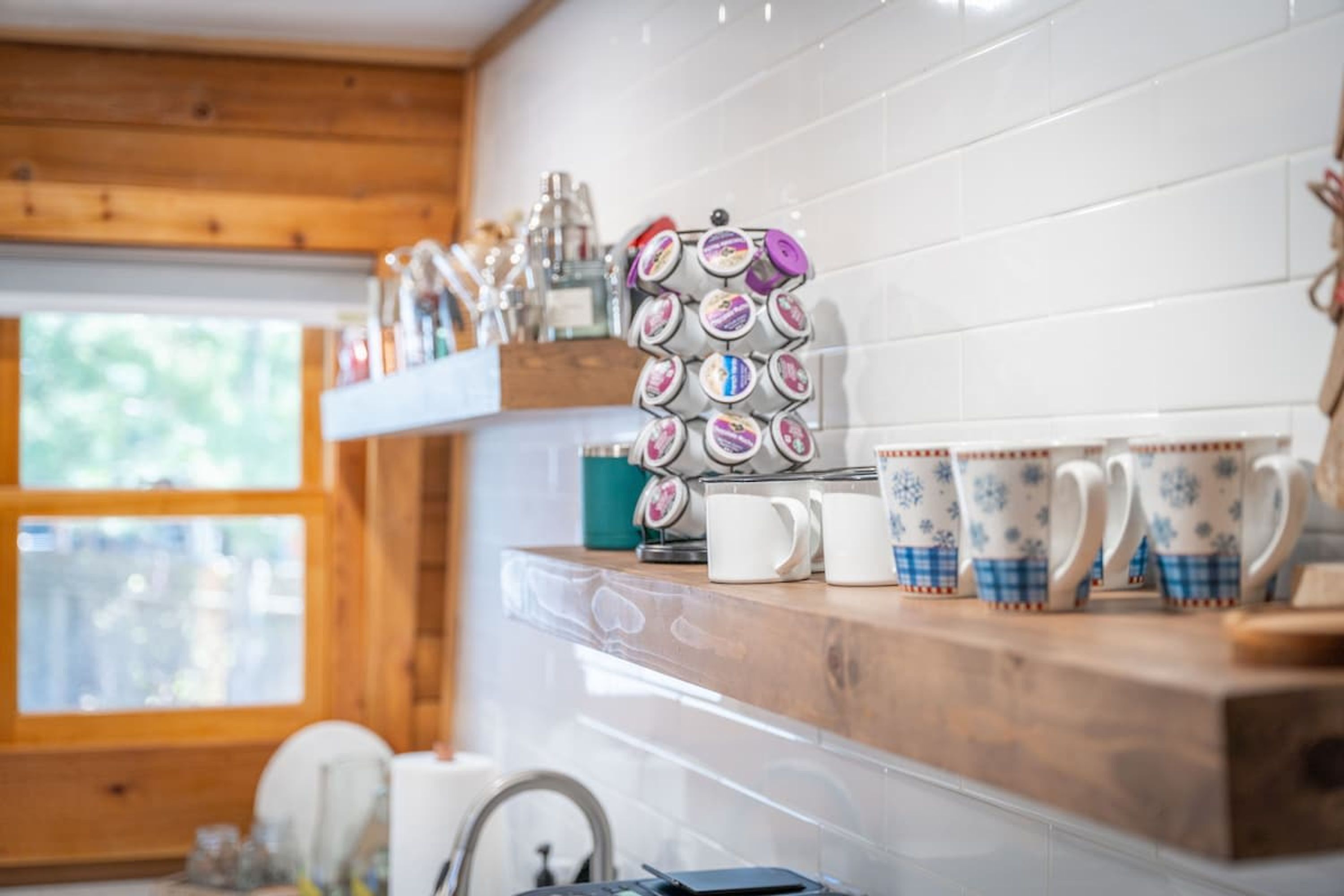 A kitchen with wooden cabinets, a coffee machine, and a variety of mugs on a shelf.