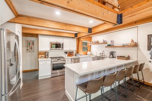 A modern kitchen with a central island, stainless steel appliances, and wooden ceiling beams. - The Canoe Cabin in Incline Village (Incline Village)