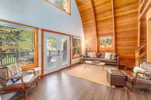 A spacious living area with a high ceiling, wooden walls, and large windows offering a view of the outdoors. - The Canoe Cabin in Incline Village (Incline Village)