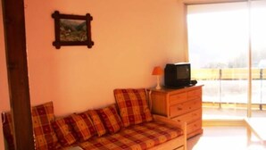 A room with a sofa, a television on a wooden cabinet, and a picture on the wall. - Studio Cabin for 4 People (Orcieres)