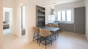 Una cocina moderna con comedor, que cuenta con una estantería para vinos empotrada, un amplio ventanal y una paleta de colores neutros.