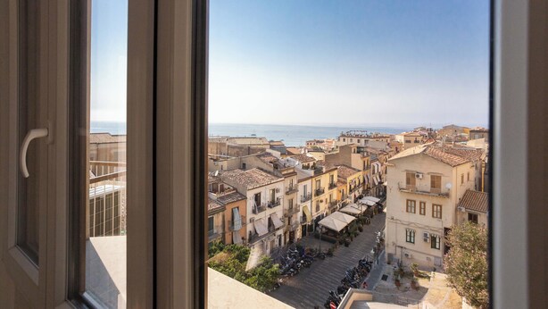 Vista desde una ventana sobre un pueblo costero con edificios y coches estacionados.