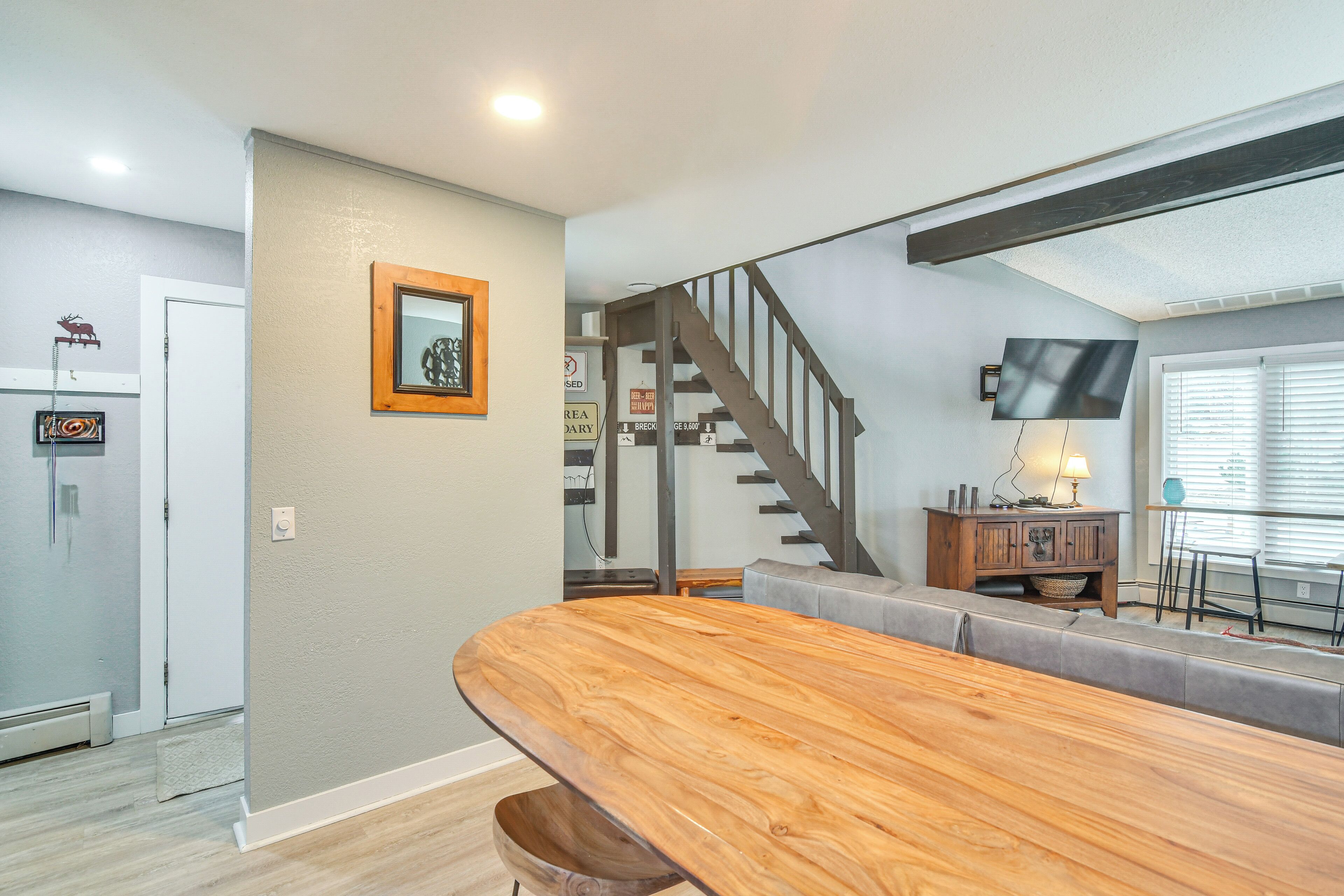 Una sala de estar moderna con un banco de madera, una escalera y un comedor.