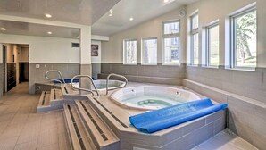 Una piscina interior moderna con jacuzzi, ventanas de vidrio transparente y piso de baldosas.