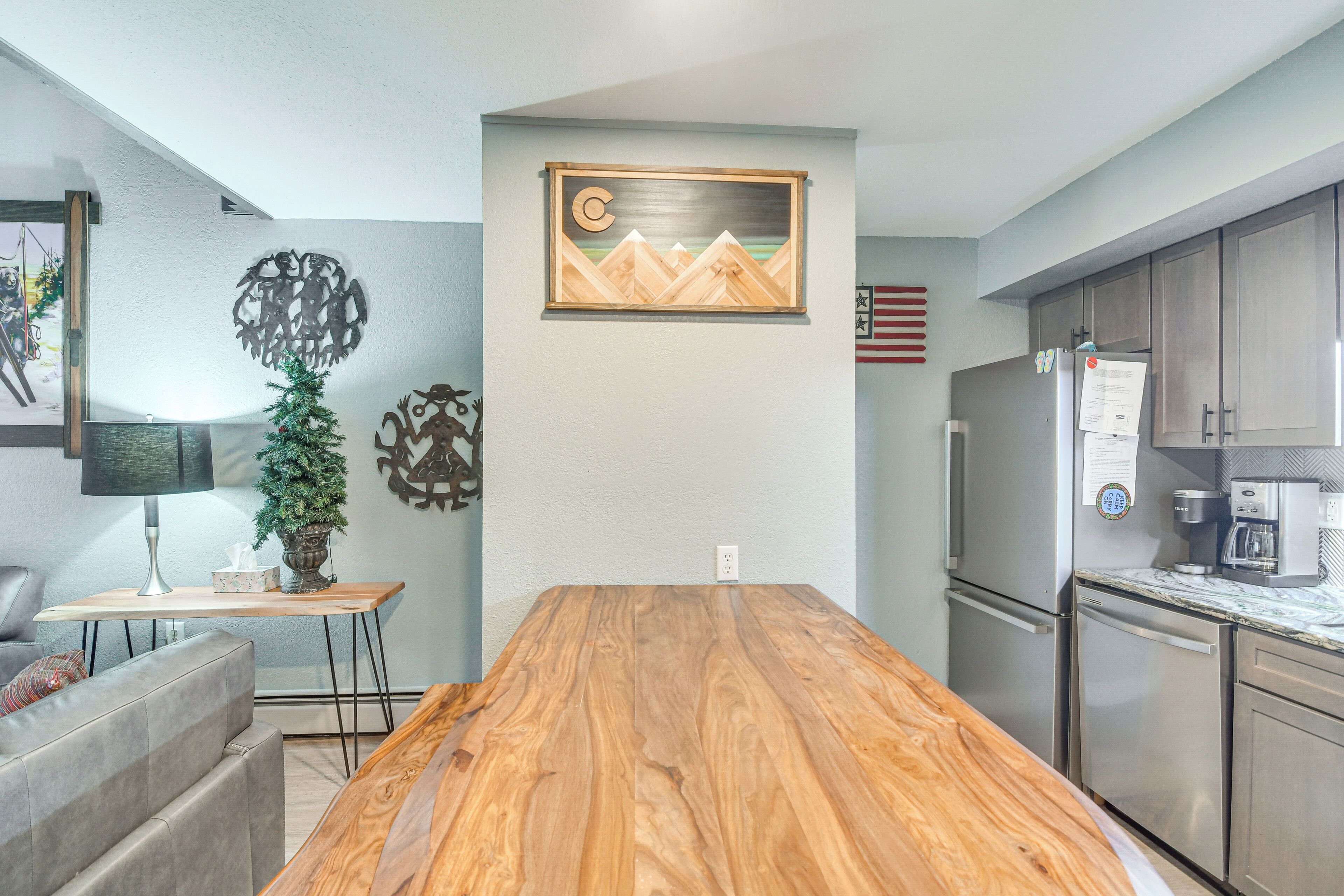 Une cuisine moderne avec un îlot central en bois, des appareils électroménagers en acier inoxydable et un tableau accroché au mur.