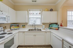 A kitchen with white cabinets, a stainless steel sink, a microwave, and a toaster. - Golf & Relax! Resort-style Condo in Myrtle Beach (North Myrtle Beach)