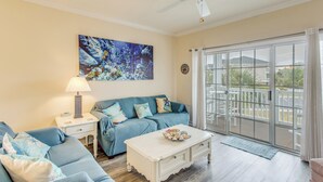A living room with a blue sofa, a white coffee table, and a ceiling fan. - Golf & Relax! Resort-style Condo in Myrtle Beach (North Myrtle Beach)
