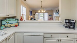 A kitchen with white cabinets, a Frigidaire dishwasher, a coffee maker, and a beach-themed sign. - Golf & Relax! Resort-style Condo in Myrtle Beach (North Myrtle Beach)
