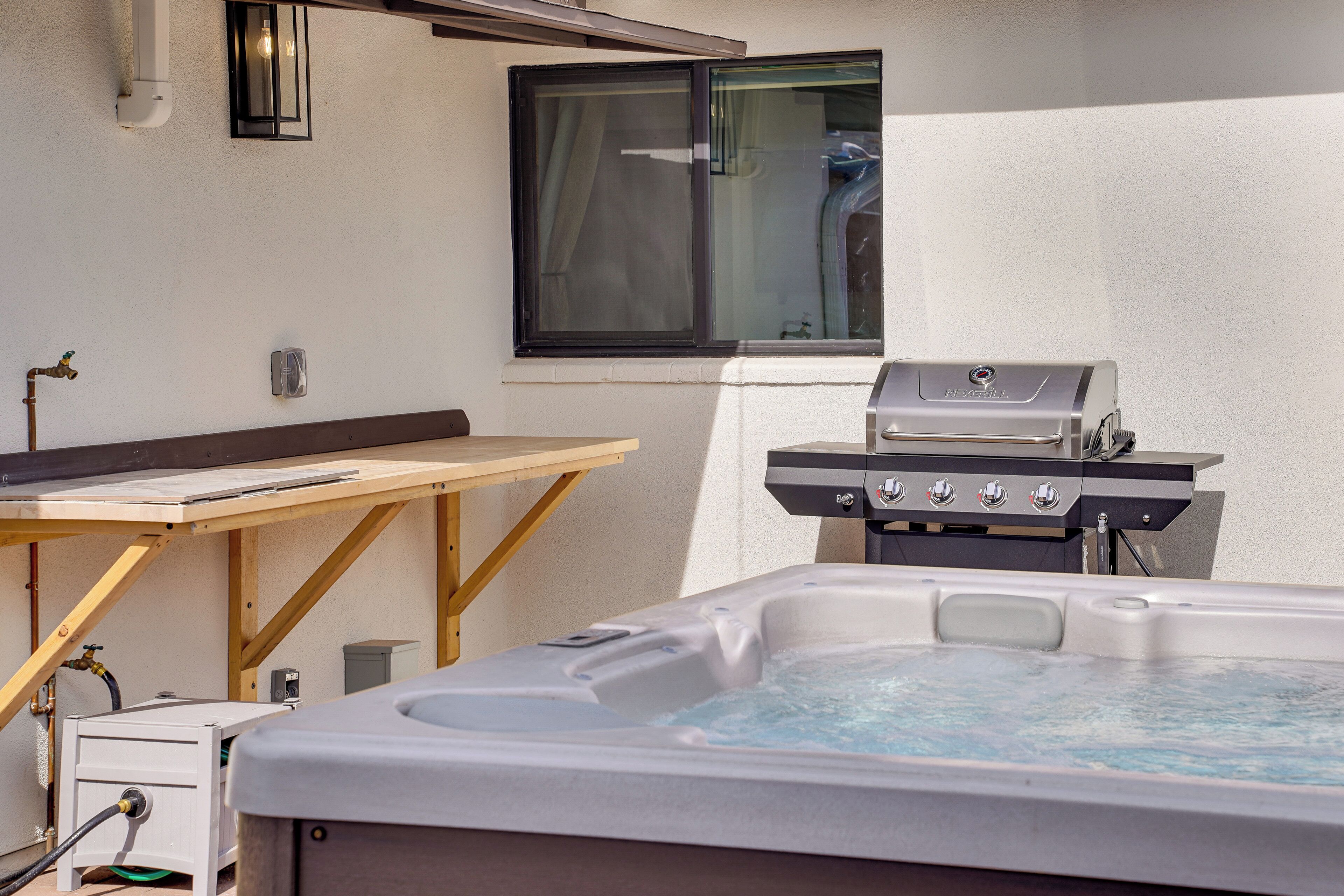 Un jacuzzi, un barbecue et une fenêtre avec des rideaux.