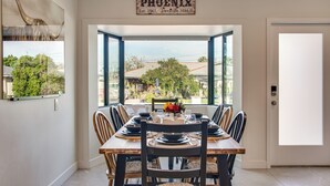 A dining area with a large window, a sign reading "PHOENIX," and a view of the neighborhood. - Fun w/ Friends! Old Town Escape w/ Outdoor Oasis (Scottsdale)