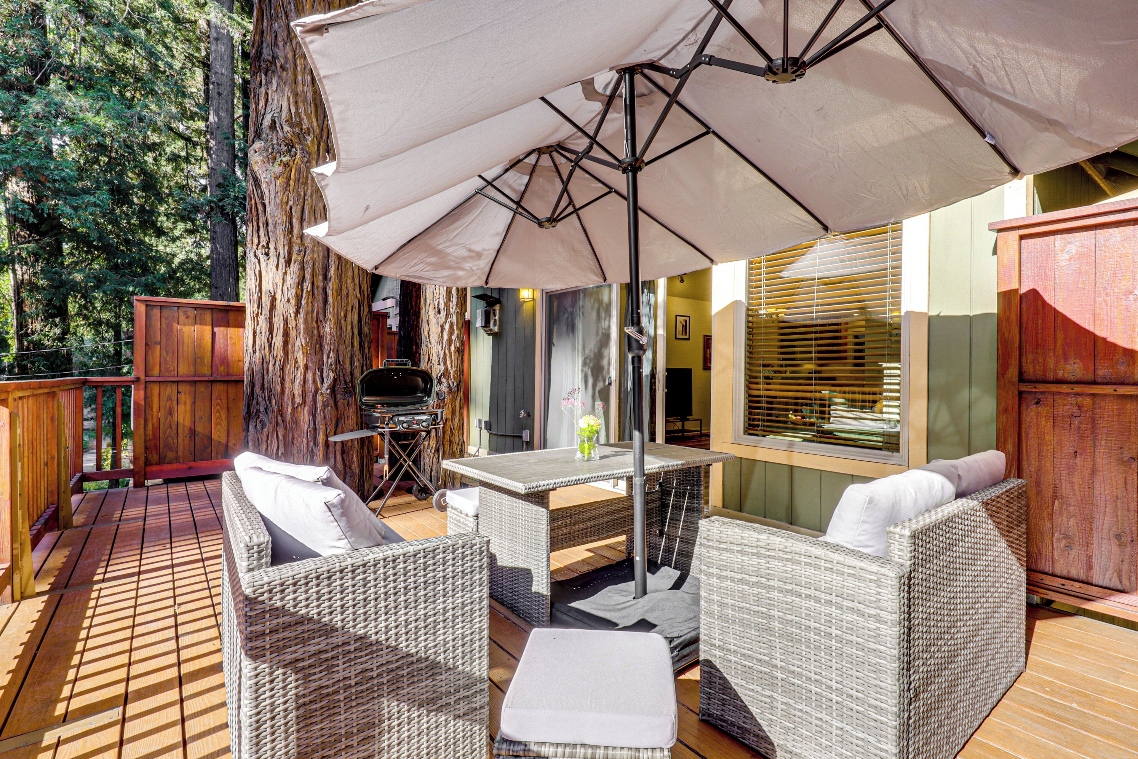 An outdoor patio area with wicker furniture, a table, and a large umbrella.